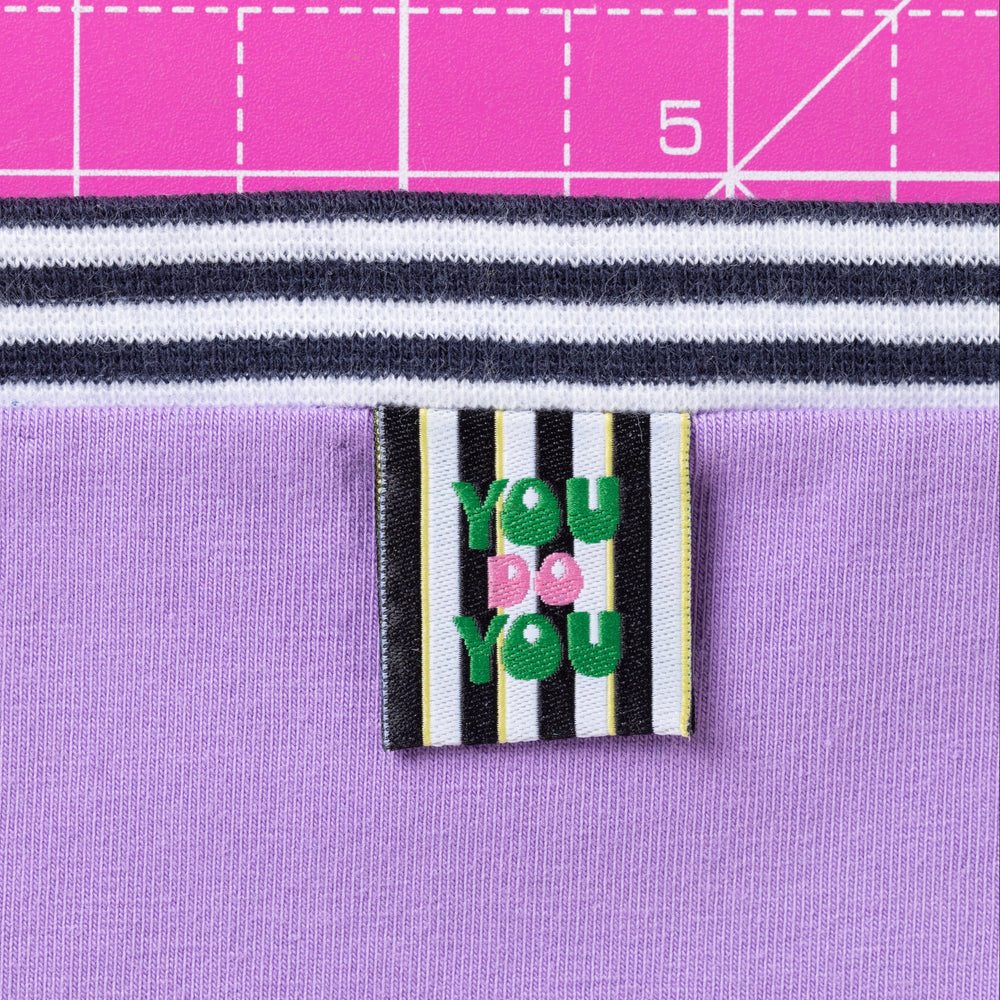 Textile with a label reading 'You Do You' on a purple fabric background