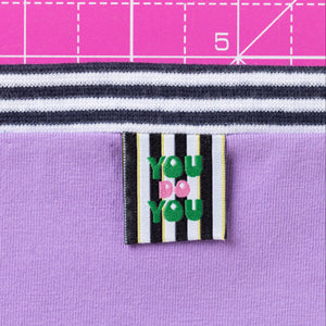 Textile with a label reading 'You Do You' on a purple fabric background